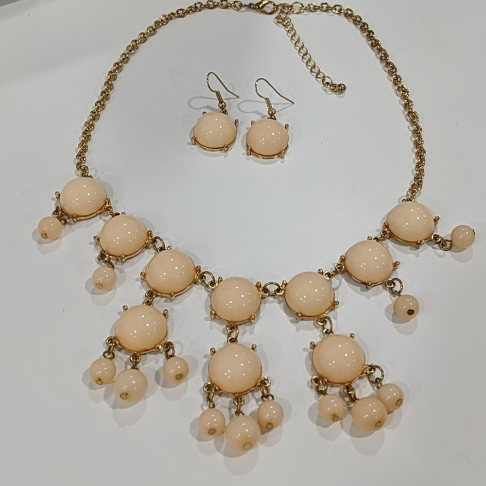 Peach colored beads on a gold toned chain.